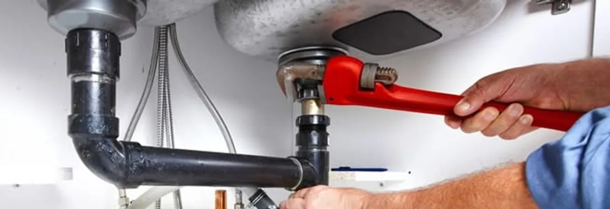 Garbage disposal repair technician tightening the sink drain and disposal connection in Akron, OH
