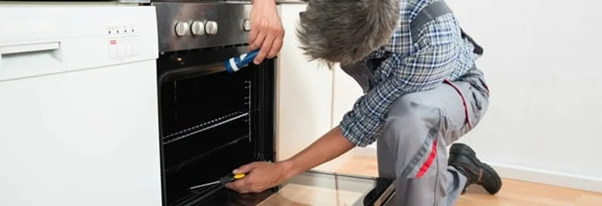 Oven repair technician inspecting and servicing an electric oven in Akron, OH