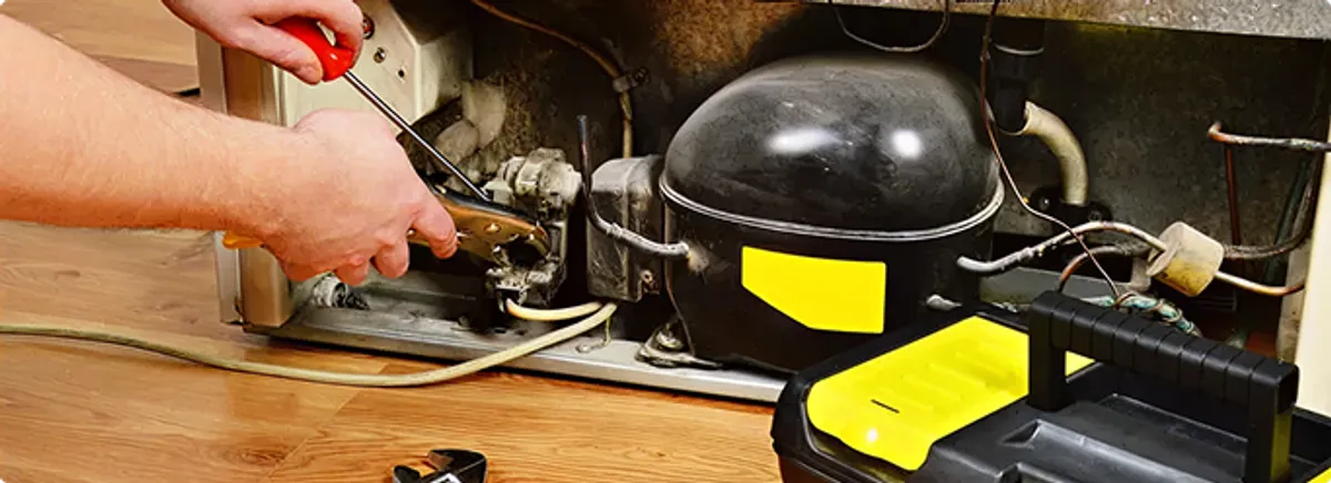 Refrigerator repair technician fixing the compressor and wiring in Akron, OH